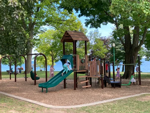 Stock Image of a playground with a green slide and lots of trees