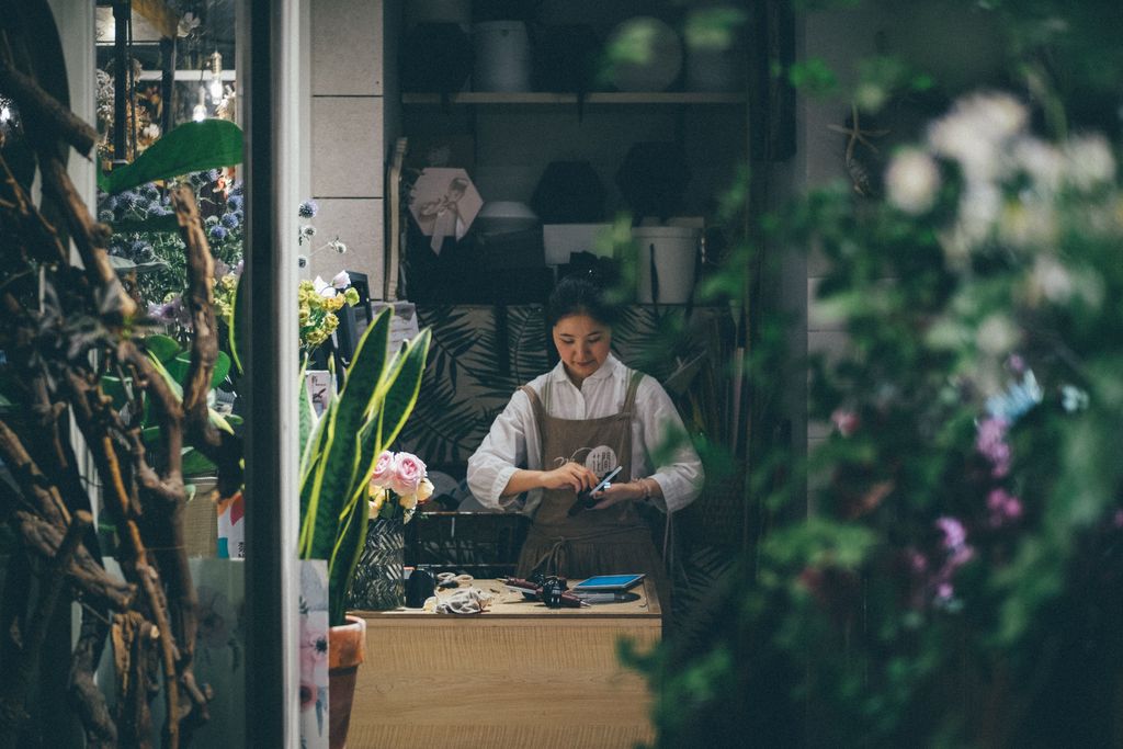 person in flower shop preparing an arrangement of flowers